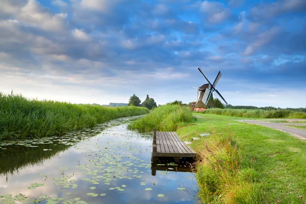 Dutch windmill by river with reflected blue sky — Stock Photo, Image