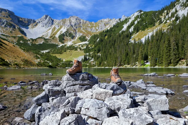 Scarpe da trekking su roccia in riva al lago alpino — Foto Stock