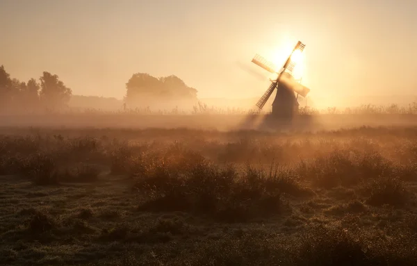 Sluníčko za větrný mlýn v ranní mlze — Stock fotografie