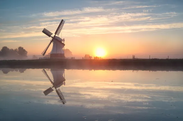 Dutch windmill reflected in river at sunrise — Stock Photo, Image