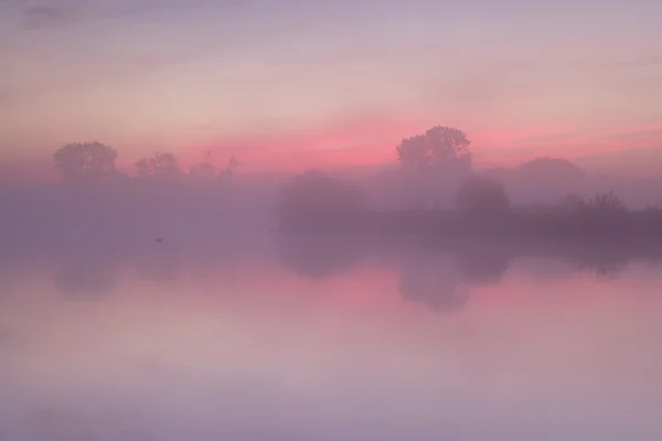 Vermelho nebuloso nascer do sol sobre lago calmo — Fotografia de Stock