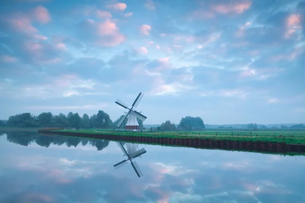 Charmante holländische Windmühle am Fluss bei Sonnenaufgang — Stockfoto