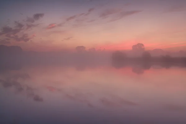 Névoa densa sobre o lago no nascer do sol dramático — Fotografia de Stock