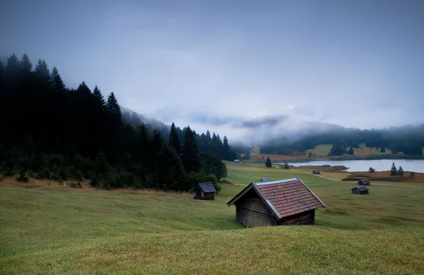 Chozas de madera y niebla sobre el lago Geroldsee al atardecer —  Fotos de Stock
