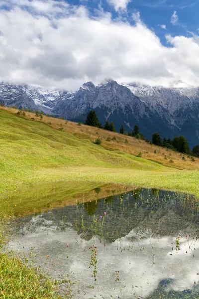 Mountains in clouds reflected in lake — Stock Photo, Image