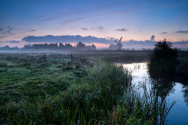 Nebliger Morgen über holländischem Ackerland mit Windmühle und Fluss — Stockfoto