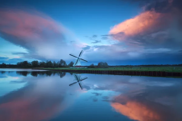 Dramatischer stürmischer Sonnenuntergang über holländischer Windmühle und Fluss — Stockfoto