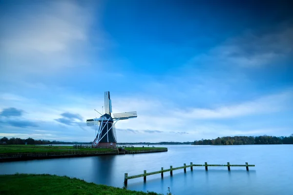 Wiatrak holenderski nad jeziorem z długim czasem naświetlania — Zdjęcie stockowe