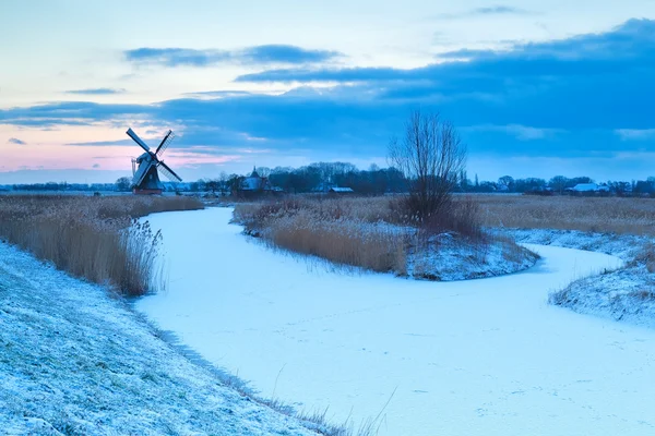 Moulin à vent et rivière gelée dans la neige — Photo