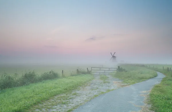 Road to Dutch windmill in morning fog — Stock Photo, Image