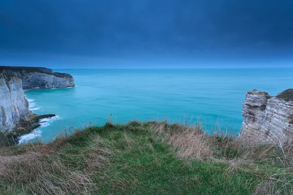 Cliffs in ocean in dusk — Stock Photo, Image