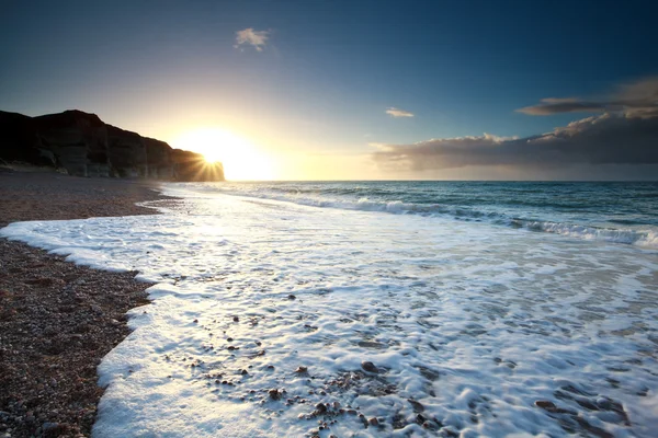 岩の多いビーチ日没で海の波 — ストック写真