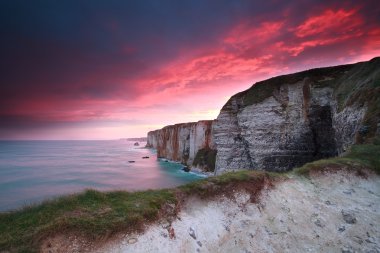 dramatic fire sunrise over cliffs in ocean clipart