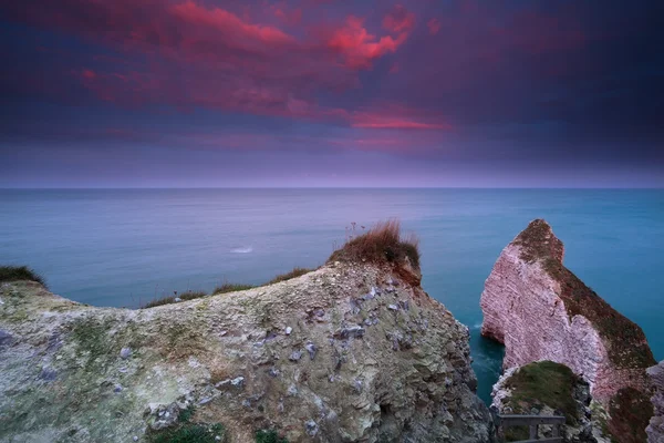 Dramatiska röd soluppgång över klippor i havet — Stockfoto