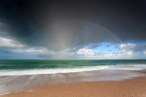 Piękna tęcza nad oceanu fale ob piasek plaża — Zdjęcie stockowe