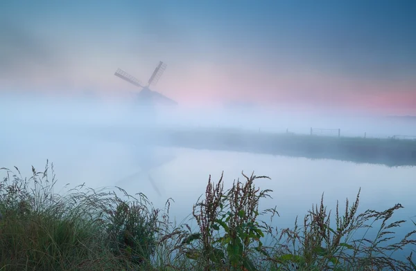 Väderkvarn silhuett i tät sunrise dimma — Stockfoto