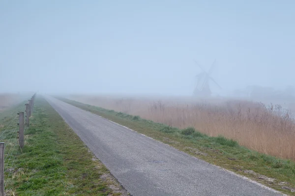 Countryside bike road and windmill in fog — Stock Photo, Image