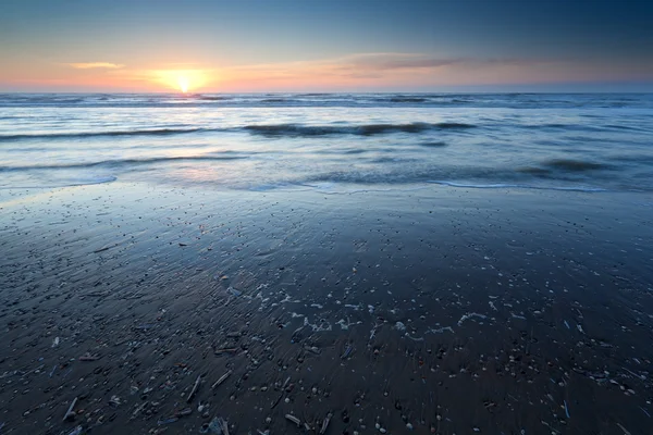 Pôr do sol sobre a praia de areia na maré baixa no mar do Norte — Fotografia de Stock