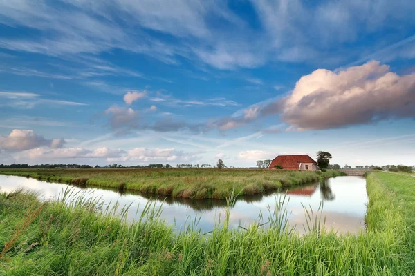 Charming farmhouse by river over blue sky — Stock Photo, Image