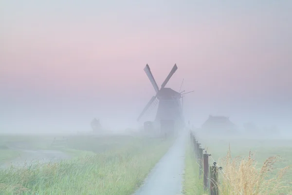 Nizozemská zemědělská půda s větrným mlýnem v mlze — Stock fotografie