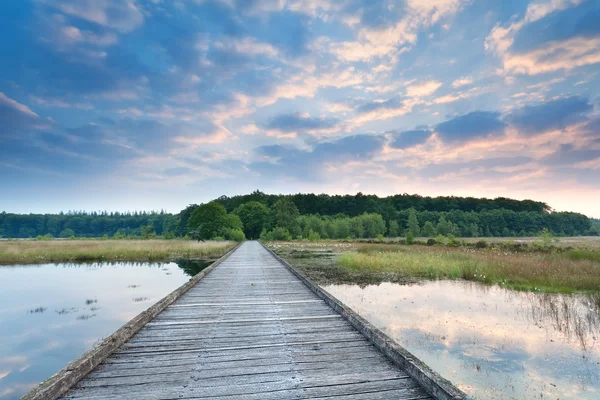 Caminho de madeira na água do lago ao nascer do sol — Fotografia de Stock
