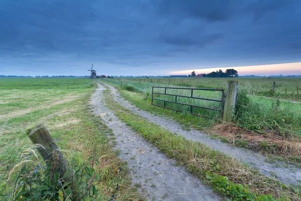 Platteland grond weg naar windmolen — Stockfoto