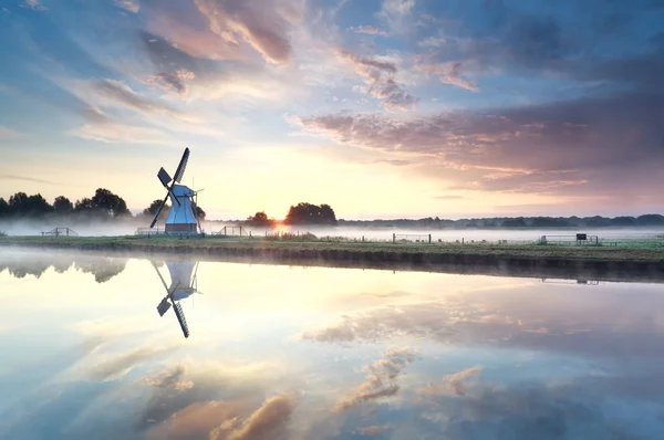Golden sunrise over windmill reflected in river — Stock Photo, Image