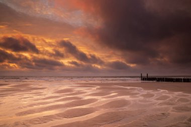 Deniz kıyısında güzel bir gün batımı alçak gelgitte, Hollanda