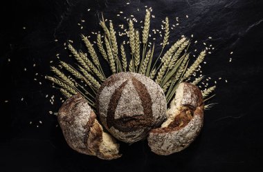 Siyah zemin üzerinde taze ekmek ve buğday taneleri