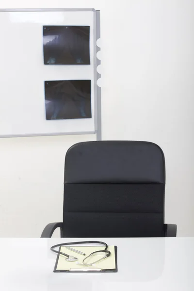 Doctor office table desk and black chair with stethoscope and w — Stock Photo, Image