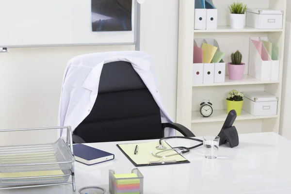 Doctor office table desk and black chair with stethoscope and w — Stock Photo, Image