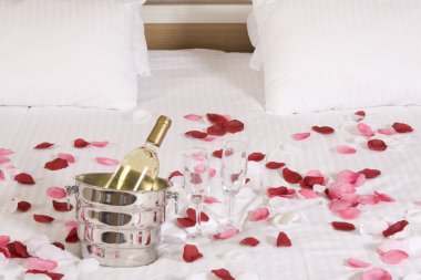 otel odasında büyük yatak ve kırmızı çiçekler