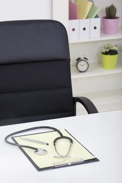 Doctor office table desk and black chair with stethoscope and w — Stock Photo, Image