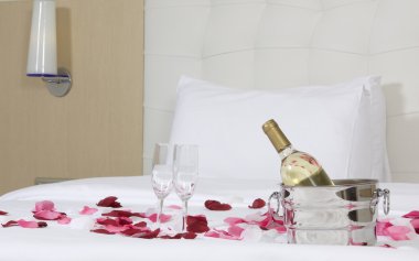 otel odasında büyük yatak ve kırmızı çiçekler