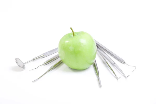 Зеленое яблоко и стоматологические инструменты изолированы на белом — стоковое фото