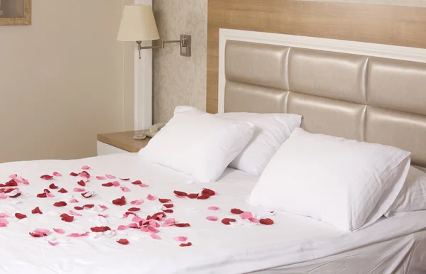 ホテルの部屋大きなベッドと赤の花を持つ — ストック写真