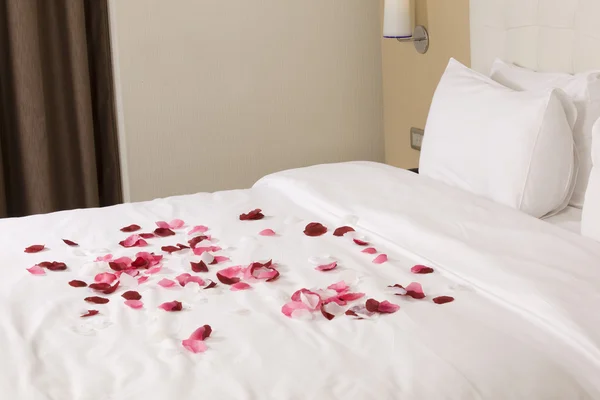 Hotel room with big bed and red flowers — Stock Photo, Image