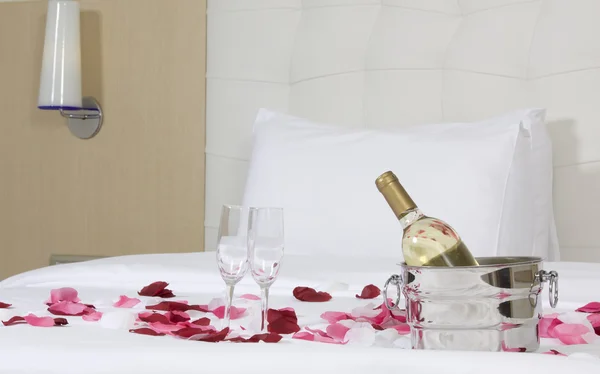 Hotellihuone, jossa iso sänky ja punaiset kukat — kuvapankkivalokuva