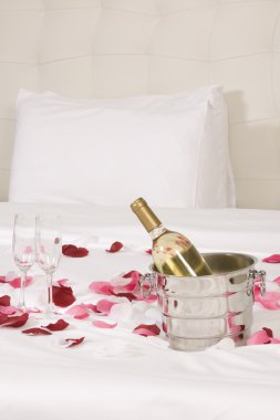 otel odasında büyük yatak ve kırmızı çiçekler