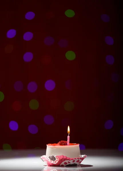 Gâteau d'anniversaire heureux tourné sur un fond flou rouge avec bougie — Photo