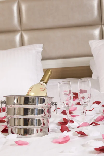 Hotelový pokoj s velkou postelí a červené květy — Stock fotografie