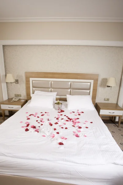 Hotelkamer met groot bed en rode bloemen — Stockfoto