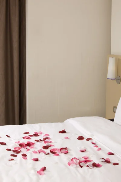 बड़े बिस्तर और लाल फूलों के साथ होटल कक्ष — स्टॉक फ़ोटो, इमेज