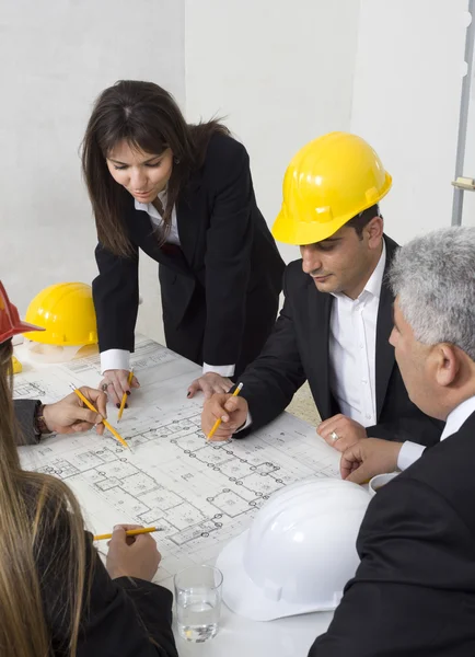 Arquitectos sentados a la mesa y mirando un proyecto — Foto de Stock