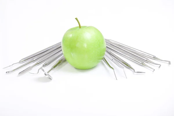 Зеленое яблоко и стоматологические инструменты изолированы на белом — стоковое фото