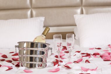 otel odasında büyük yatak ve kırmızı çiçekler