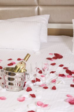 otel odasında büyük yatak ve kırmızı çiçekler