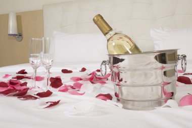 otel odasında büyük yatak ve kırmızı çiçekler