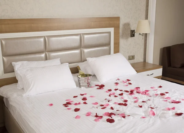 Hotellrum med stor säng och röda blommor — Stockfoto