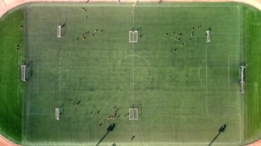 Futbol sahasında futbol oynayan çocukların hava görüntülerini çeken bir dronun üst görüntüsü.